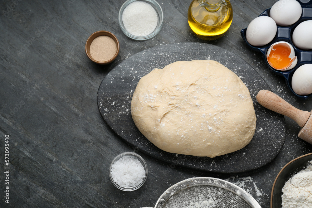 Fresh yeast dough and ingredients on black table, flat lay. Space for text Fresh yeast dough and ingredients on black table, flat lay. Space for text
