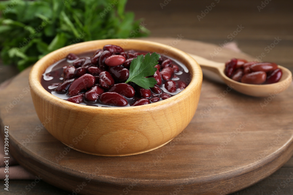 Bowl of canned red kidney beans with parsley on wooden table, closeup Bowl of canned red kidney beans with parsley on wooden table, closeup