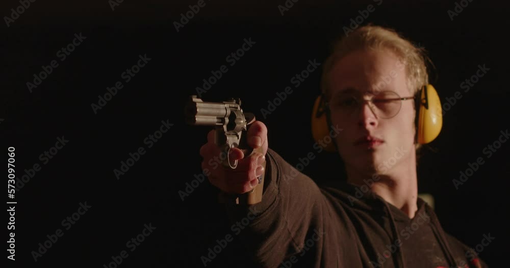 Young man shooting a revolver in dark room