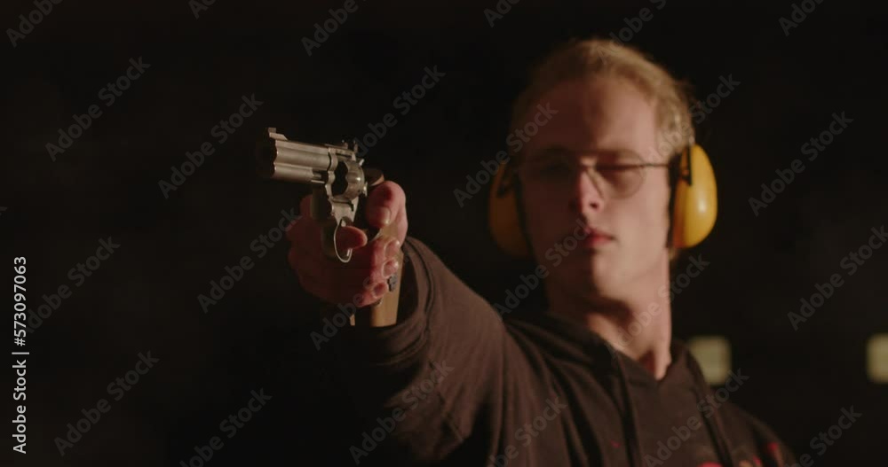 Close up of young man aiming a revolver off screen and shooting in slow motion Close up of young man aiming a revolver off screen and shooting in slow motion