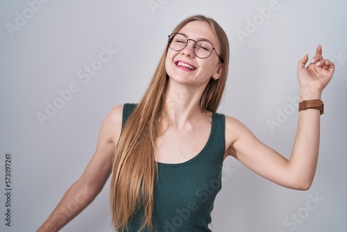 Young caucasian woman standing over white background dancing happy and cheerful  smiling moving casual and confident listening to music