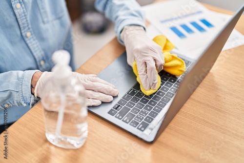 Young hispanic man business worker cleaning laptop at office