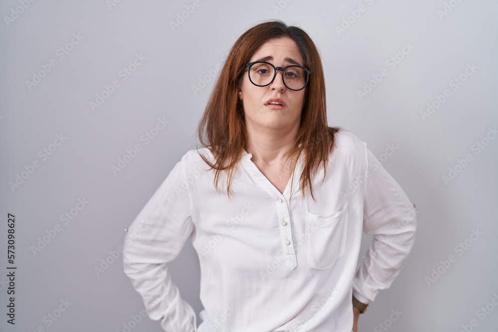 Brunette woman standing over white isolated background looking sleepy and tired, exhausted for fatigue and hangover, lazy eyes in the morning.