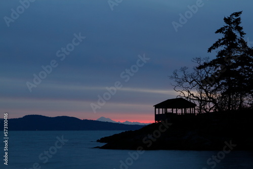 Wooden shelter and tree in silhouette at blue hour sunrise on the ocean