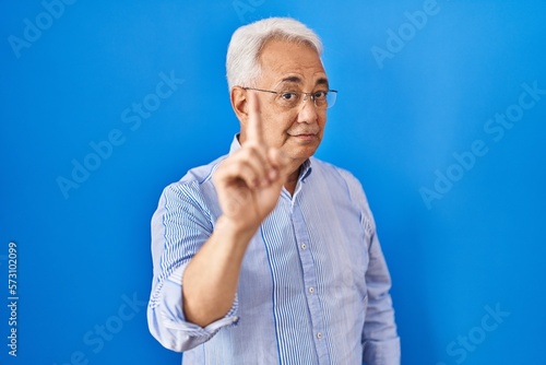 Hispanic senior man wearing glasses pointing with finger up and angry expression, showing no gesture © Krakenimages.com