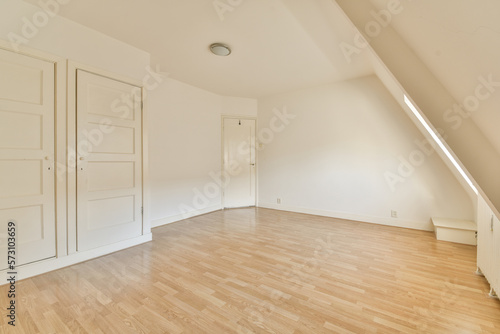 an empty room with wood flooring and white doord closets on the right hand side of the room photo