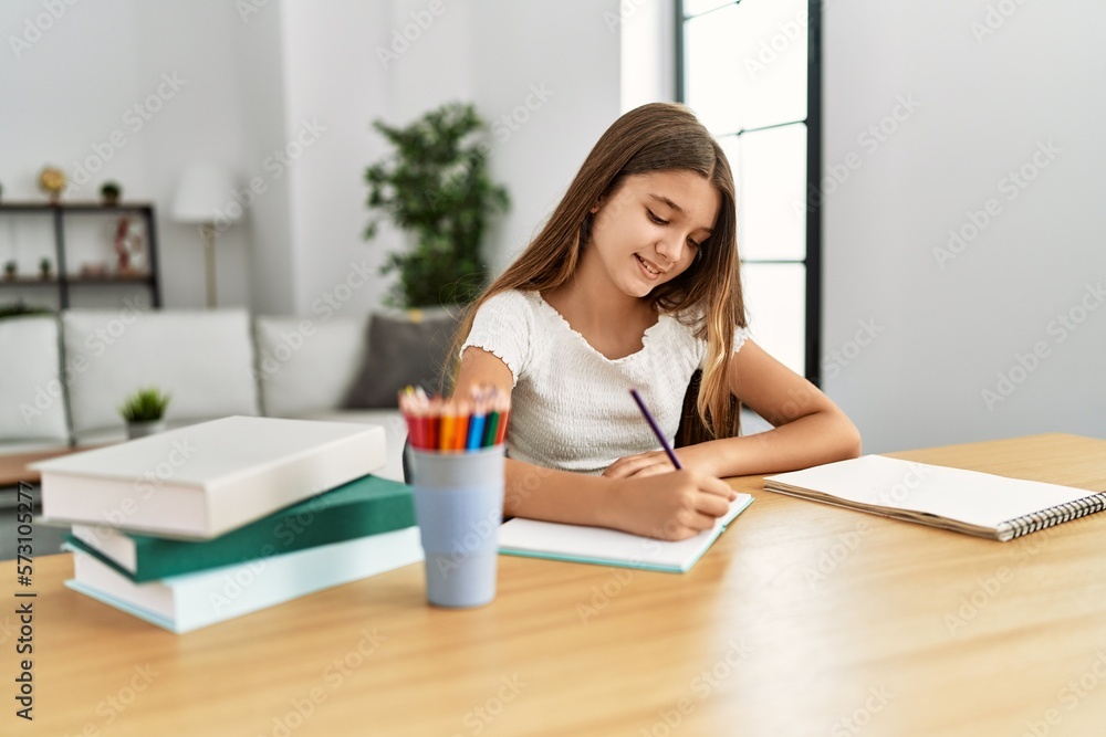 Adorable girl doing homework sitting on table at home Adorable girl doing homework sitting on table at home