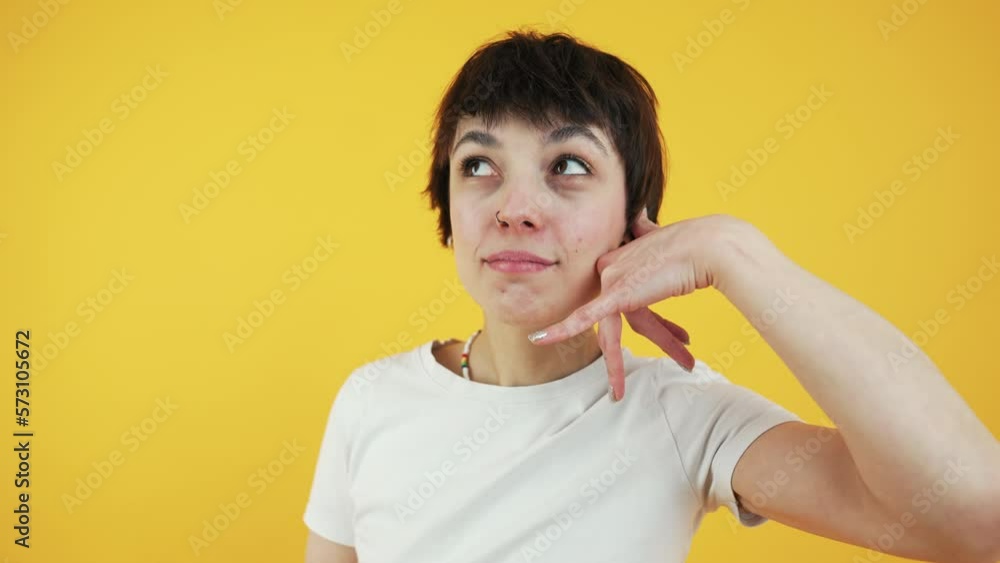 Laid-back boyish-looking girl posing to the camera with a smile and doing Shaka or call me sign. Medium studio shot over orange background. High quality 4k footage Laid-back boyish-looking girl posing to the camera with a smile and doing Shaka or call me sign. Medium studio shot over orange background. High quality 4k footage