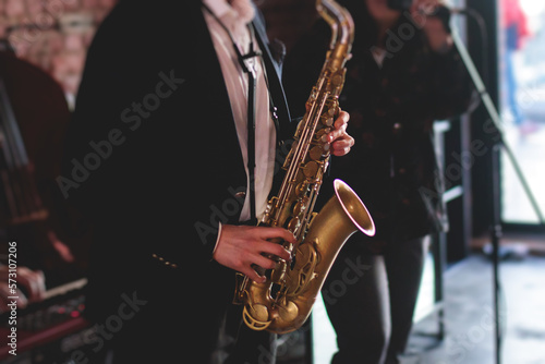 Concert view of saxophonist  a saxophone sax player with vocalist and musical band during jazz orchestra show performing music on a stage in the scene lights