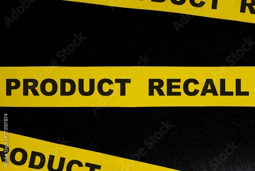 Product recall alert, caution and warning concept. Yellow barricade tape with word in dark black background. photo
