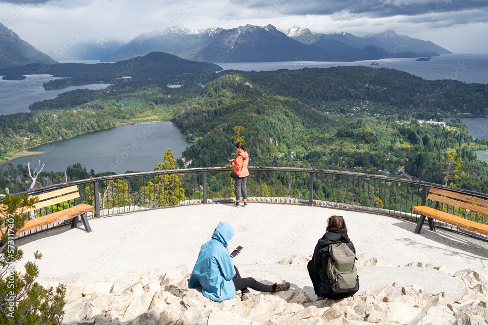 Tres jóvenes damas están en el mirador del Cerro Campanario observando las bellezas del paisaje de Bariloche Argentina.	
