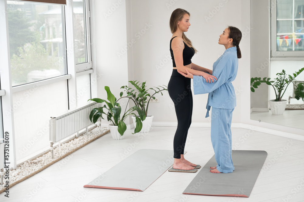 Caucasian woman stands on sadhu boards with therapist support. Caucasian woman stands on sadhu boards with therapist support.