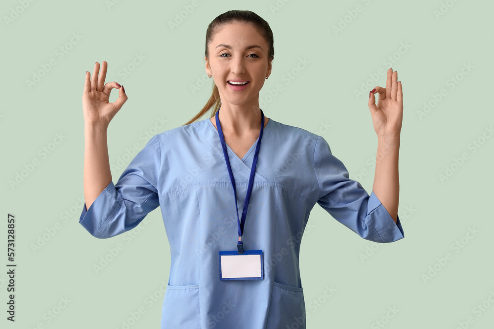 Female medical intern with badge showing OK on green background Female medical intern with badge showing OK on green background