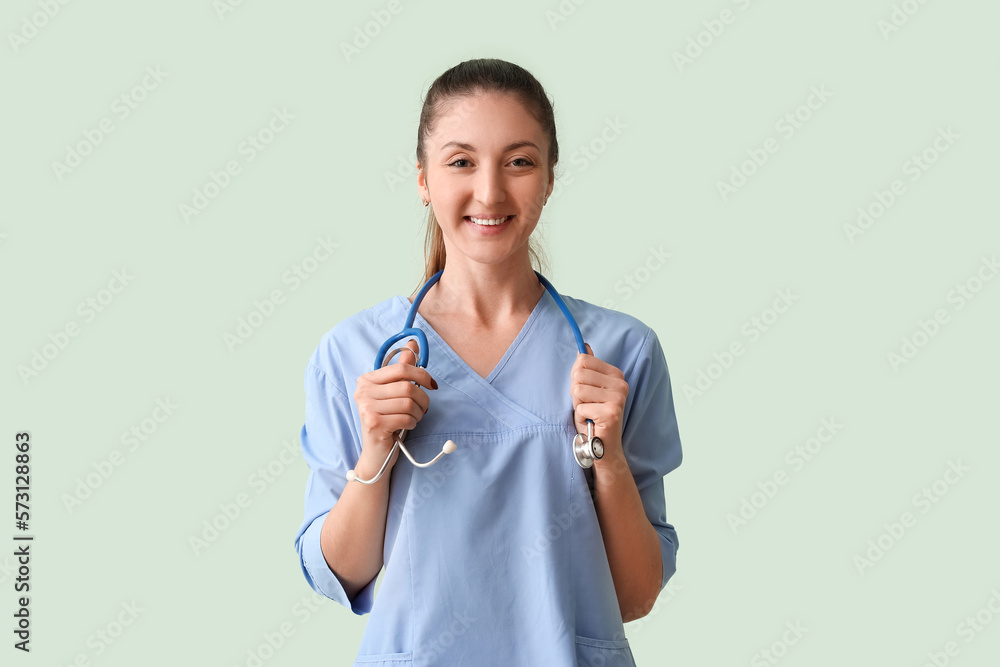 Female medical intern with stethoscope on green background Female medical intern with stethoscope on green background
