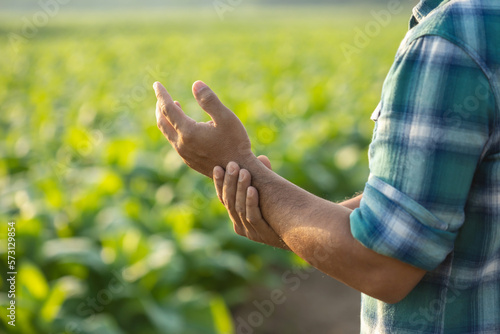 Injuries or Illnesses that can happen to farmers while working. Man is using his hand to cover over wrist because of hurt, pain or feeling ill.