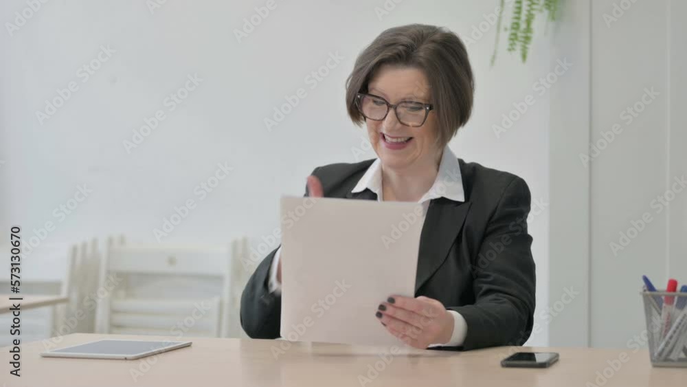 Old Businesswoman Celebrating Success while Reading Documents in Office Old Businesswoman Celebrating Success while Reading Documents in Office