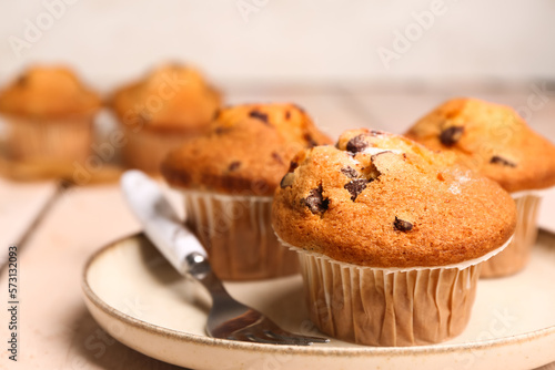 Plate of tasty muffins on light wooden table, closeup