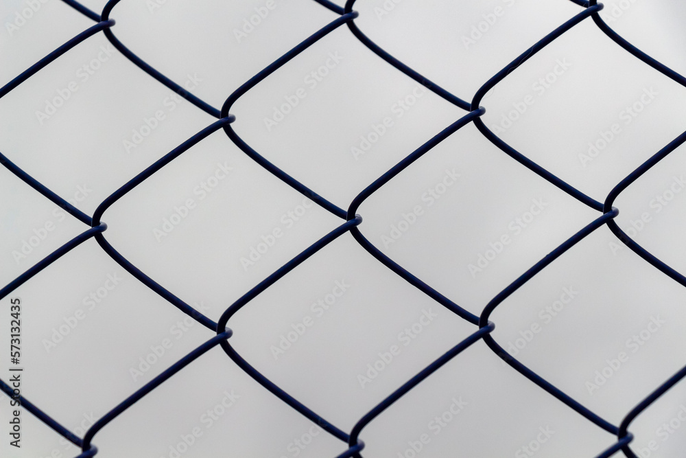 Fototapeta premium Chain-link fence against a gloomy gray sky.