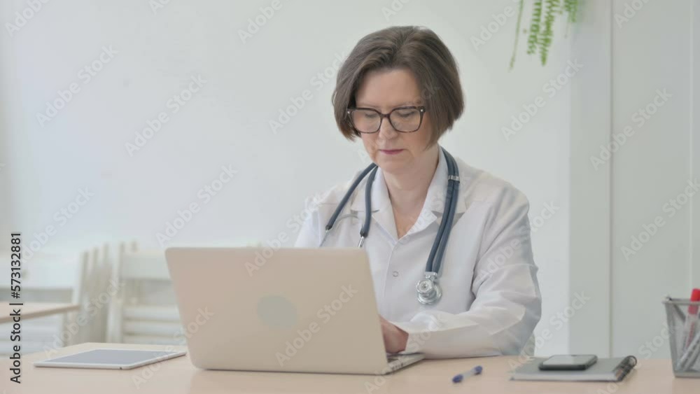 Senior Doctor Typing on Laptop in Clinic Senior Doctor Typing on Laptop in Clinic