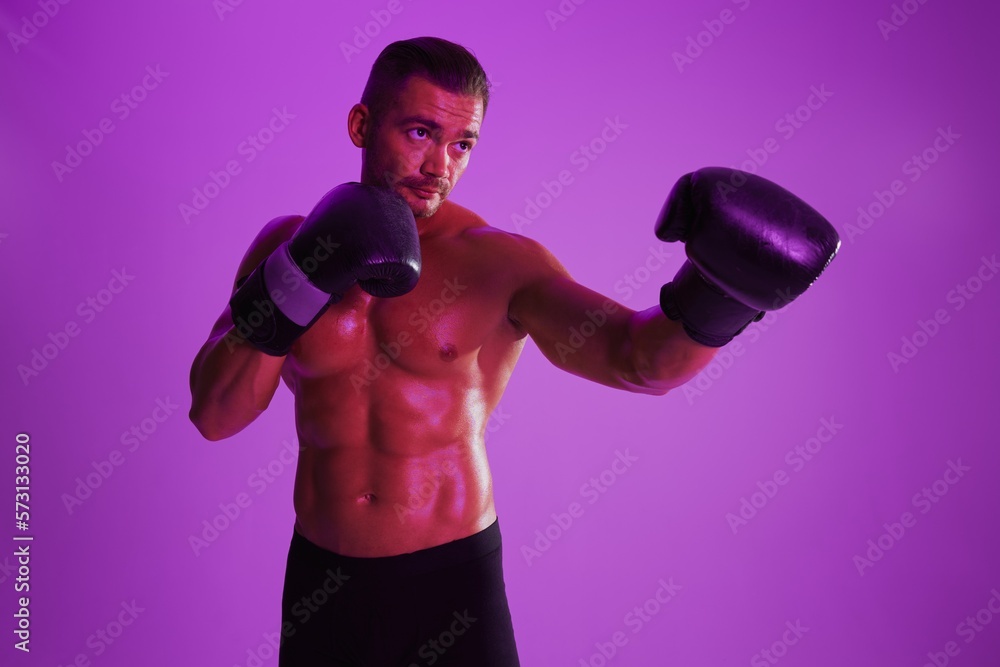 Man bodybuilder boxer muscle workout with naked torso. Advertising, sports, active lifestyle, colored purple light, competition, challenge concept. 