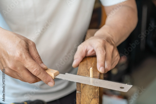 Carpenter using Japanese saw or pull saw , Cutting Wooden Dowels on wood on table , DIY maker and woodworking concept. selective focus