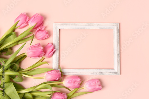 Beautiful tulip flowers and blank wooden frame on pink background © Pixel-Shot