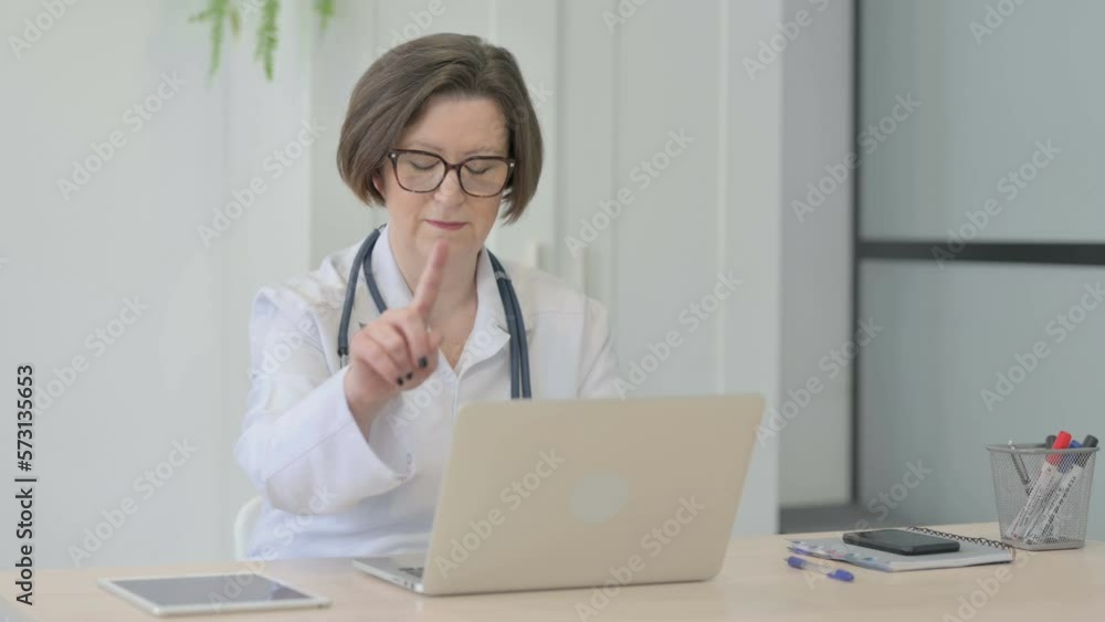 Old Female Doctor Shaking Head in Rejection while Working on Laptop Old Female Doctor Shaking Head in Rejection while Working on Laptop