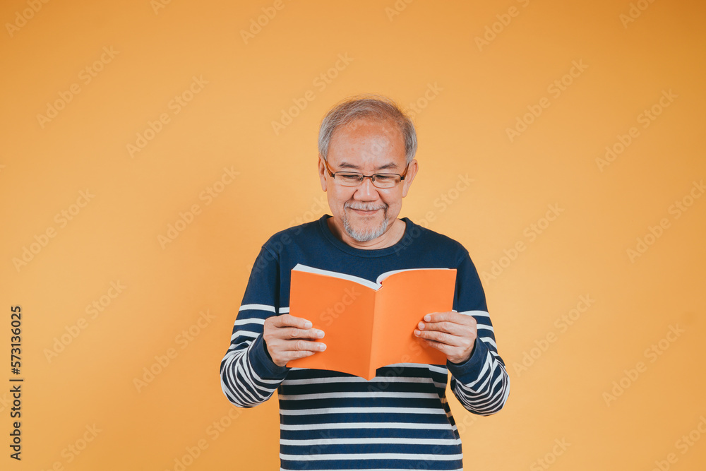 Happy positive senior male smiling and read book education knowledge learning on color background. Happy positive senior male smiling and read book education knowledge learning on color background.
