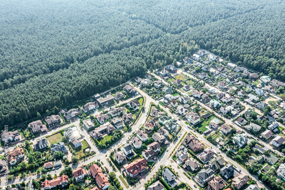 aerial view of suburban neighborhood near green forest  in a sunny summer day. drone photo.