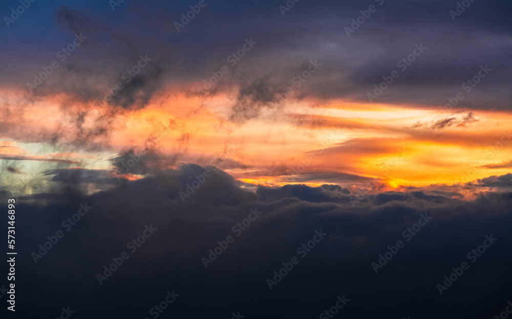 Beautiful sunrise sky. Wallpaper image with amazing coloured orange and dark blue layers of clouds. Nature landscape.