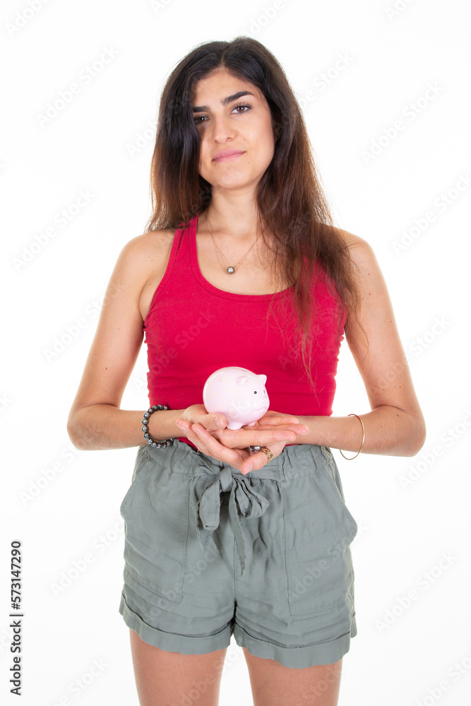 Young caucasian woman holding pink small piggy bank on white background Young caucasian woman holding pink small piggy bank on white background