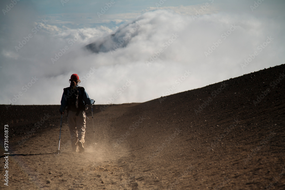 A woman in her thirties carrying an infant hikes in the high-elevation volcanic Haleakala crater. A woman in her thirties carrying an infant hikes in the high-elevation volcanic Haleakala crater.