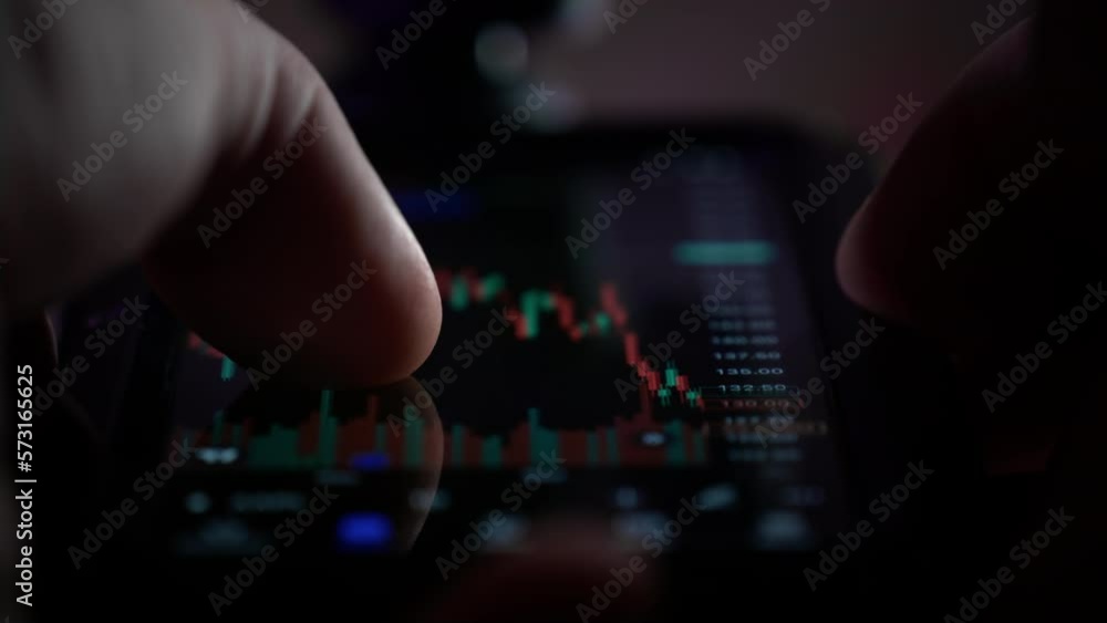A man holds a smartphone in his hands, buys stocks, deals with crypto and trading. The male palm has a phone, controls the fingers on the screen in the investment management application. Neon light A man holds a smartphone in his hands, buys stocks, deals with crypto and trading. The male palm has a phone, controls the fingers on the screen in the investment management application. Neon light