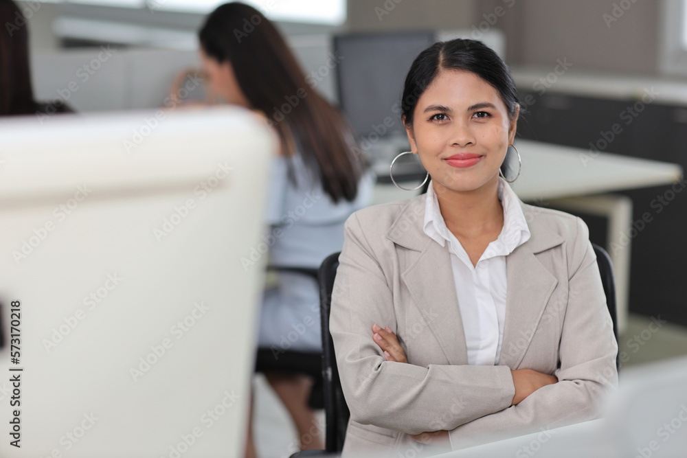 Portrait of confident and beautiful young asian businesswoman with happy emotion sitting and arms cross with confident after using computer in modern office. Success business concept Portrait of confident and beautiful young asian businesswoman with happy emotion sitting and arms cross with confident after using computer in modern office. Success business concept