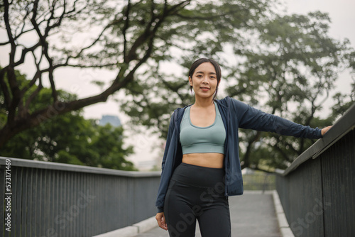 Asian happy woman exercise in park on morning. Healthy confident female wearing sportswear standing and smiling in outdoors. wellness lifestyle, outside activities. © sarayutsridee