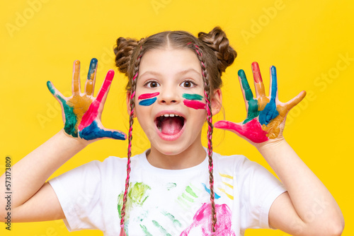 A little girl shows her palms stained with paint. Painting and drawing for children. A child with paints on an isolated background.