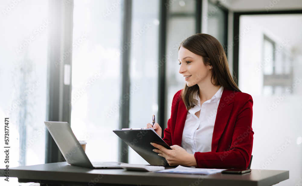 Young beautiful woman typing on tablet and laptop while sitting at the working wooden table modern office. Young beautiful woman typing on tablet and laptop while sitting at the working wooden table modern office.