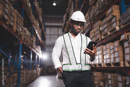 Black male staff using digital tablet working checking stock in logistic warehouse