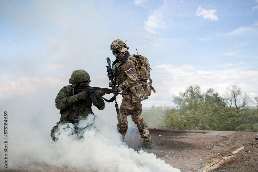 Two soldiers in the war shoot from a machine gun in the smoke