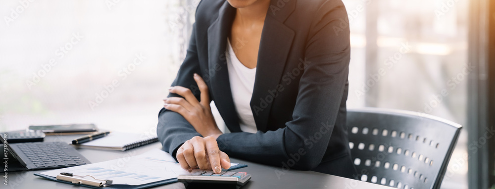 Business woman working on laptop and accounting financial report, accountant using calculator to calculate tax refund at office. - obrazy, fototapety, plakaty 