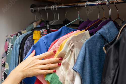 a woman near the closet chooses a T-shirt for her to wear.