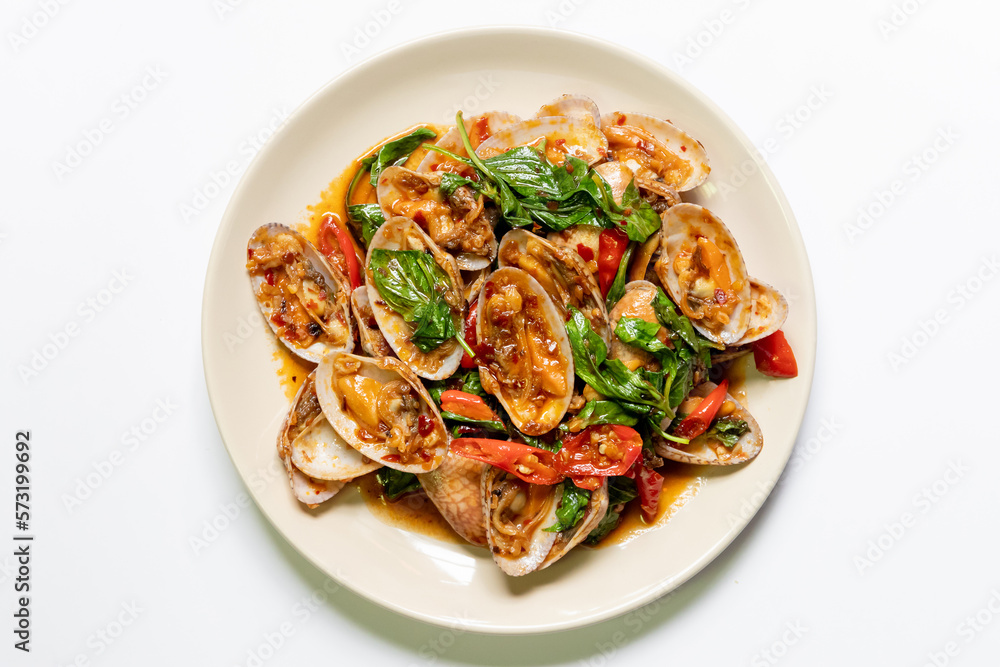 Stir-fried clams with chili paste and sweet basil on white plate. 