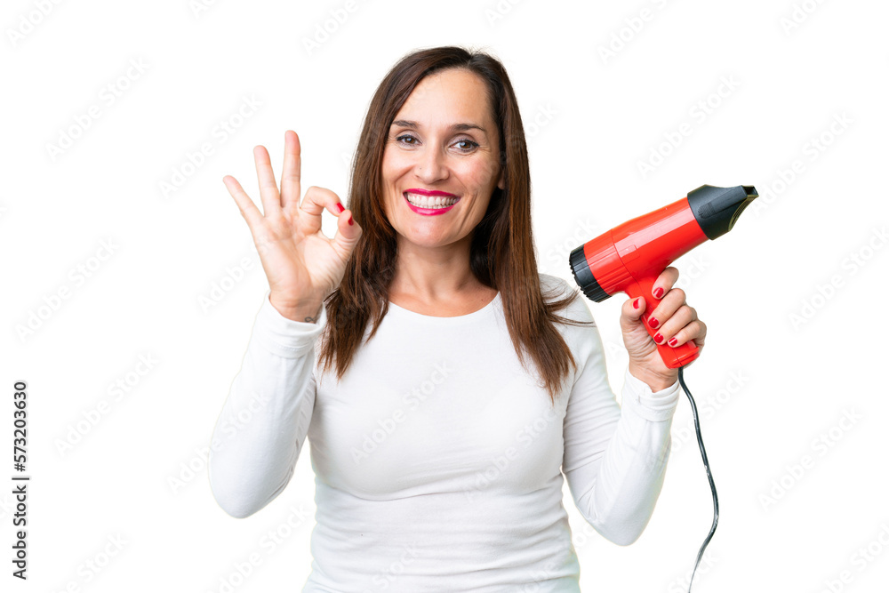 Middle age woman holding a hairdryer over isolated chroma key background showing ok sign with fingers Middle age woman holding a hairdryer over isolated chroma key background showing ok sign with fingers