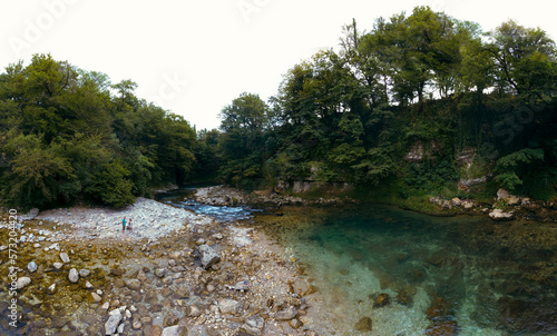 The Abhesi waterfall  couple tourists man and woman  a mountain river with clear water. the stones are turned by the stream. Tourist place for rest and swimming. Aerial view. western Georgia