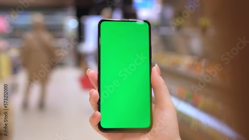 4k Mobile phone Chroma key for mobile app application. Close up of woman hand holds smart phone with green screen at shopping mall store. Buying food at supermarket, grocery shop center online