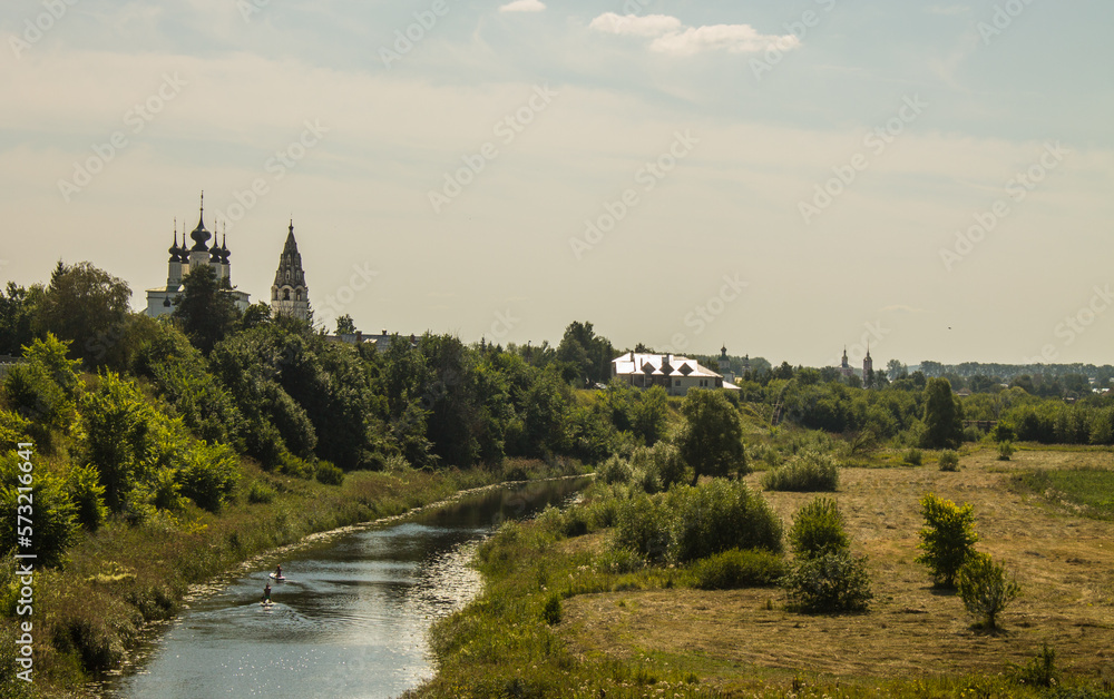 Panoramic view of the historical architecture of Suzdal in the Vladimir region among the green foliage of trees and Kamenka river on a sunny summer day and a space for copy