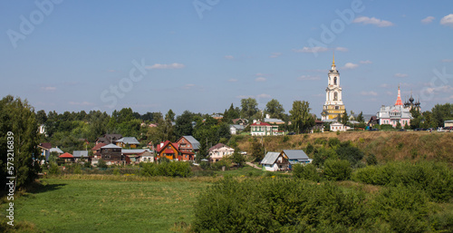 Beautiful panoramic landscape - the old town of Suzdal with a bell tower and historical architecture among green trees and grass on a sunny summer day and a space to copy