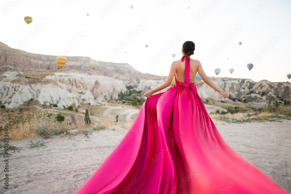 a girl in a flying dress with a long train on the background of balloons in Cappadocia. a girl in a flying dress with a long train on the background of balloons in Cappadocia.