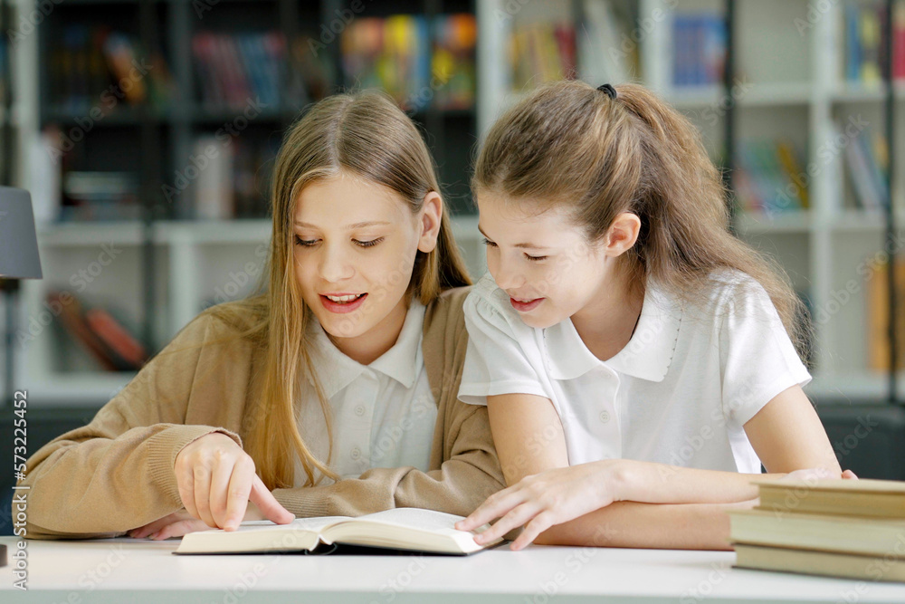School children sitting at desk together, reading funny book and laughing, friends having fun in class. Pupils studying in class. Concept of education School children sitting at desk together, reading funny book and laughing, friends having fun in class. Pupils studying in class. Concept of education