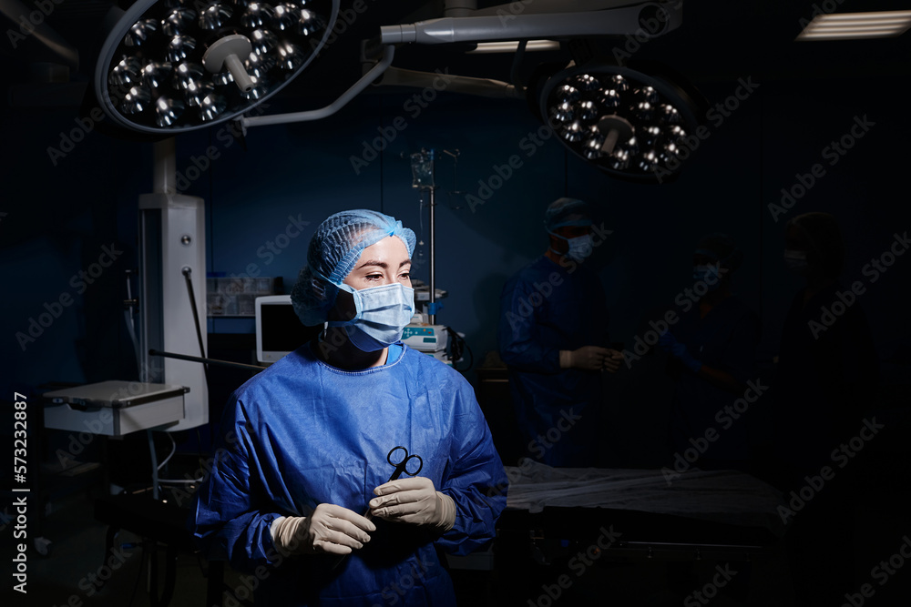 Illuminated portrait of operating theatre nurse wearing PPE with
